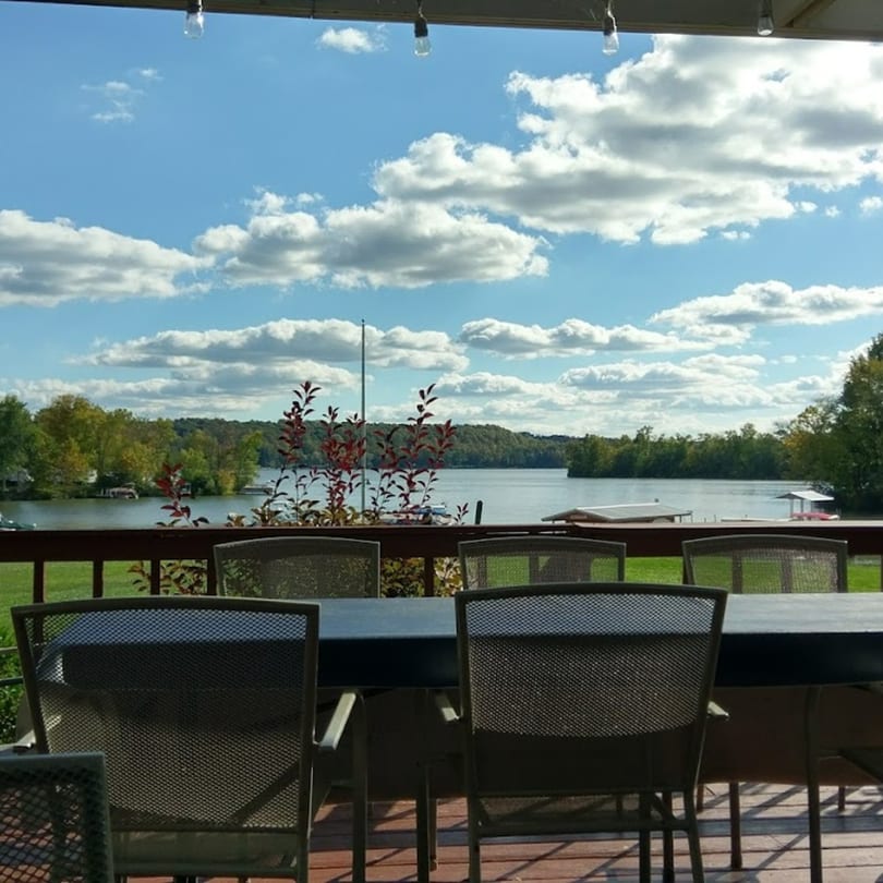 Outdoor dining area at Lighthouse Bistro with a scenic view of Atwood Lake and a cloudy sky.